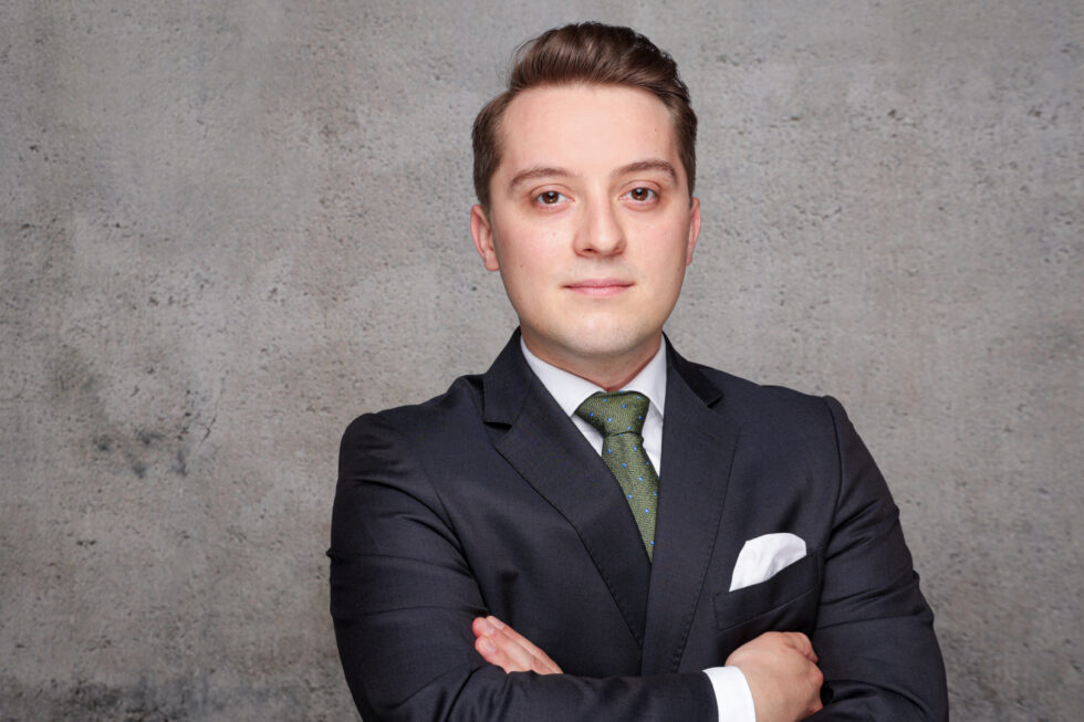 The portrait photo of a man in a suit, against a neutral background.